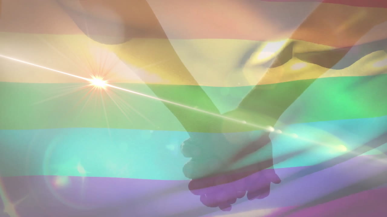 Clasped silhouette hands radiating unity in flat style with rainbow pride stripes and sunburst glow