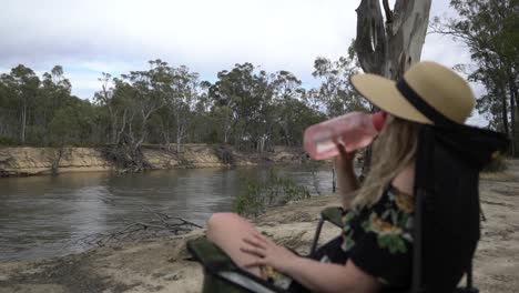 mujer sentada en una silla de camping bebiendo agua en un caluroso día australiano