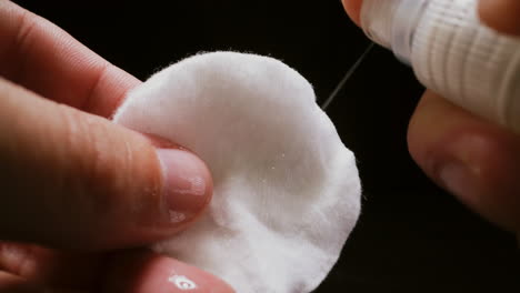 person sprays antiseptic onto cotton pad to clean germs