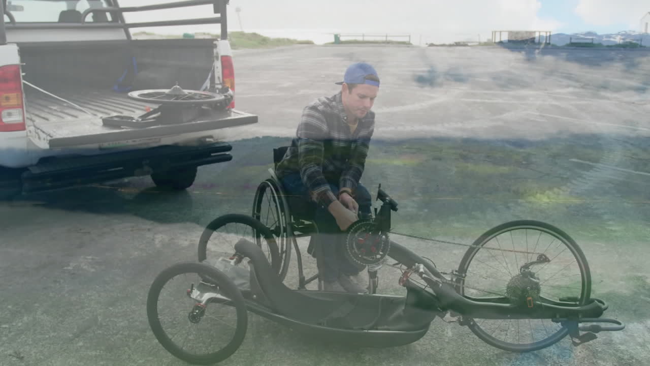 Assembling handcycle, man in wheelchair near parked truck on coastal road