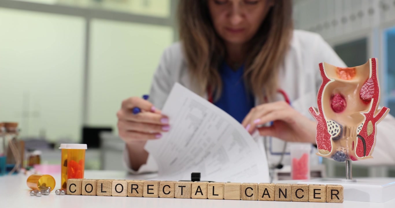 Le parole 'cancro colorettale' e un medico che compila le cartelle cliniche dei pazienti.