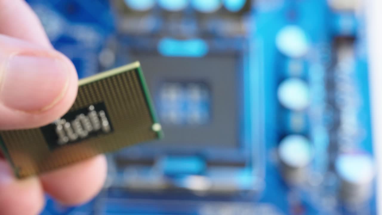 mano sujetando el procesador de cpu de microchip y colocándolo en el zócalo de la placa base borrosa, macro extrema