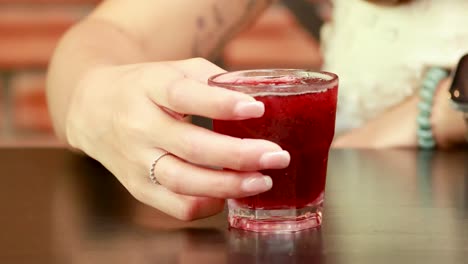 Two people clink glasses filled with red drinks in a warm, inviting atmosphere. Natural lighting enhances the celebratory mood
