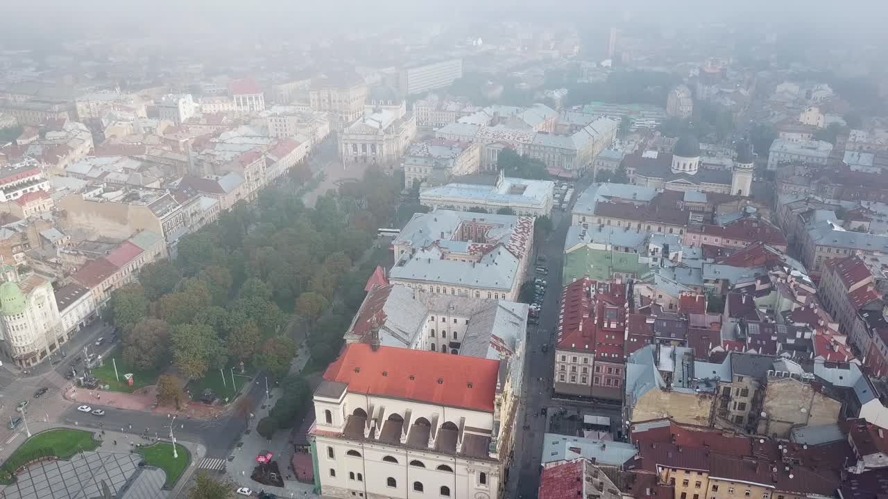 Beautiful view of the city center with old buildings and green park in Lviv, Ukraine. Aerial view of roofs of houses in Lviv. Camera moves top down.