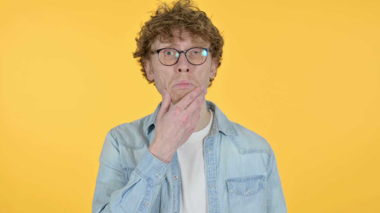 joven pelirrojo sintiéndose conmocionado, fondo amarillo