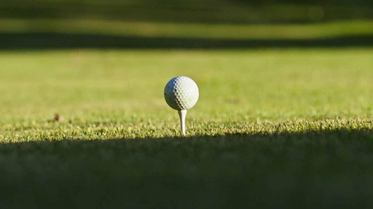 Primo piano estremo di un driver da golf che colpisce una palla dal tee al rallentatore. Ripresa di dettaglio cinematografica che cattura impatto, precisione e potenza su un campo da golf a Verbier, Svizzera.