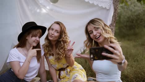 Fröhliche-Kaukasische-Mädchen,-Die-Selfie-Auf-Dem-Smartphone-Machen.-Junge-Süße-Frauen-Mit-Sinnlichem-Gesichtsausdruck.-Draußen-Auf-Einem-Plaid-Im-Gras-Sitzen.-Freundschaft,-Picknick,-Bachelorette-Konzept