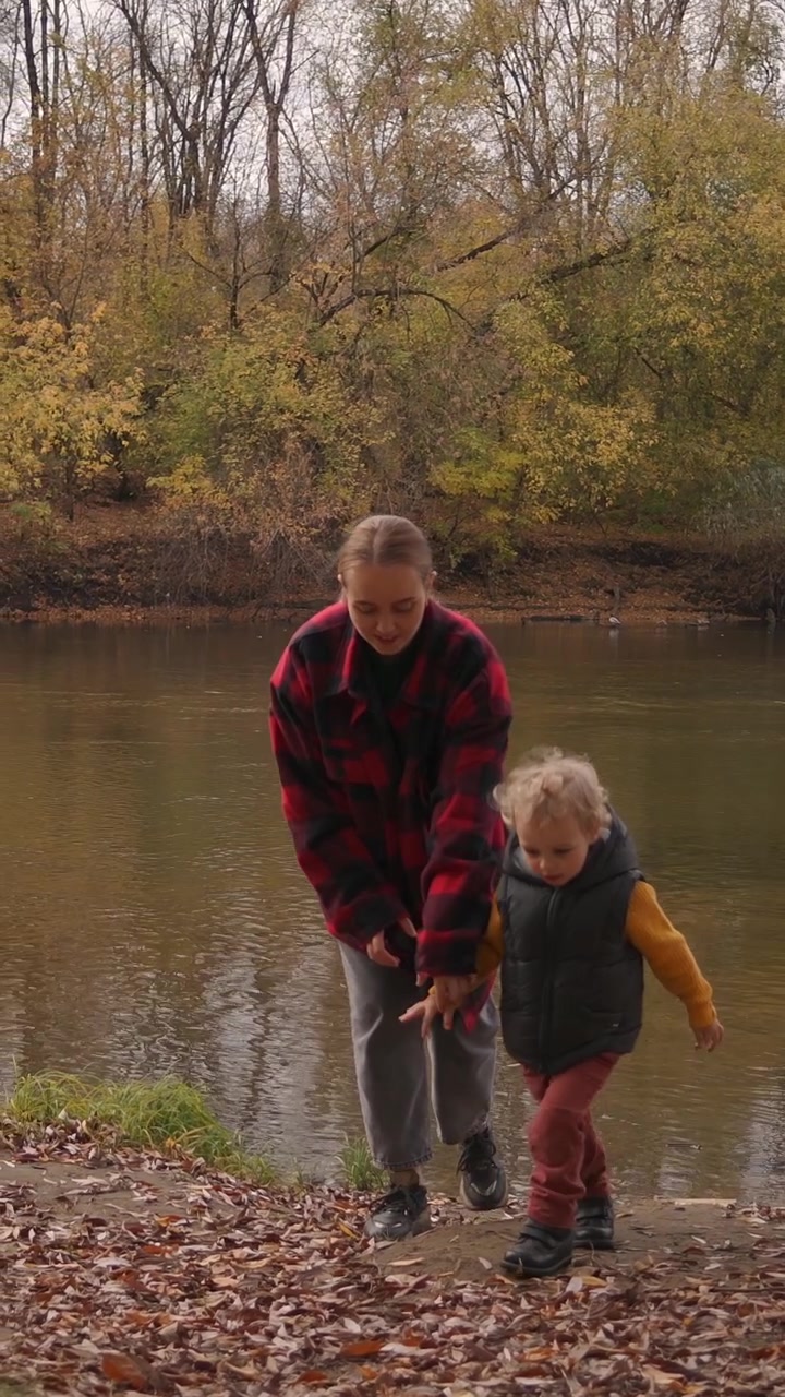 Giovane Donna e Bambino che Camminano Insieme Lungo un Fiume in Autunno
