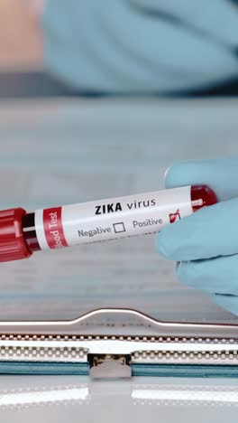 healthcare professional examines blood test tube labeled zika virus in lab