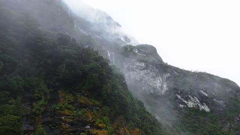 mist slowly rises above cliffside giving eerie awe inspiring feeling as waterfall reveals