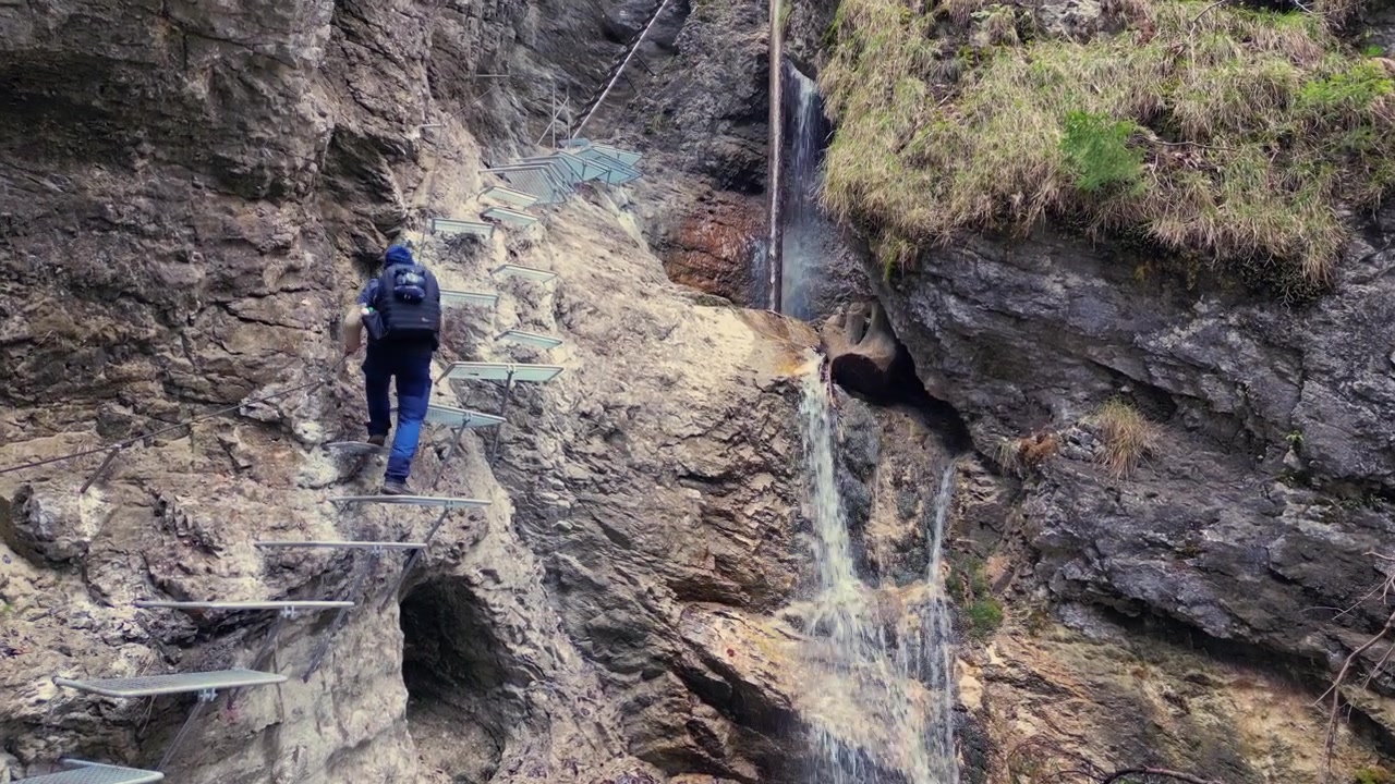 Man with a backpack walking along a challenging via ferrata trail inside Sucha Bela canyon in Slovak Paradise National Park