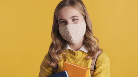 Glückliches-Kaukasisches-Teenagermädchen-Mit-Gesichtsmaske,-Das-Bücher-Hält.