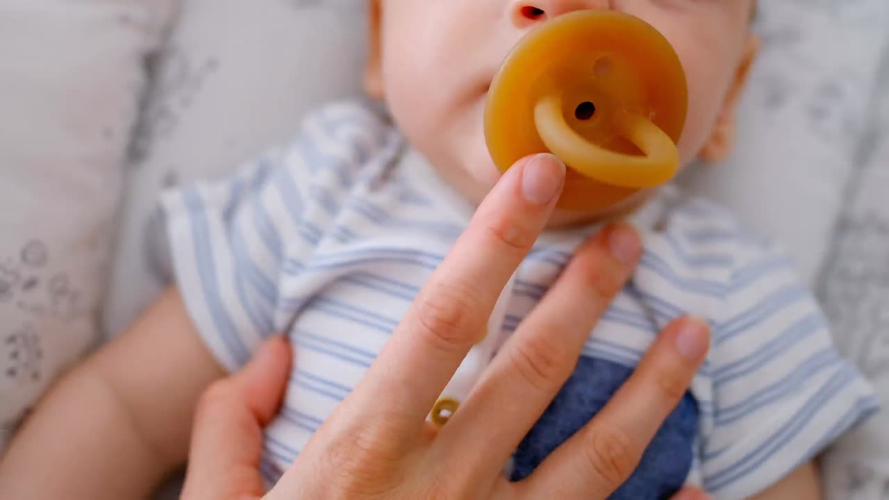 엄마의 손이 귀여운 아기를 만지고 집에서  ⁇ 청이와 함께 침대에서 누워 있습니다.