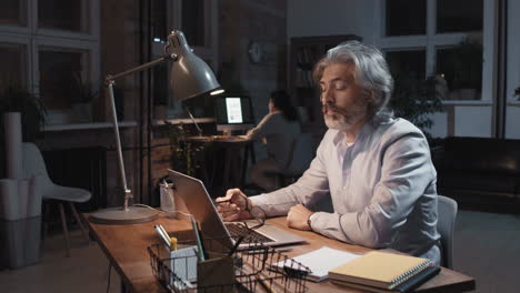 man working late at night on laptop in an office