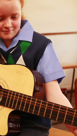 un alumno lindo tocando la guitarra en el aula