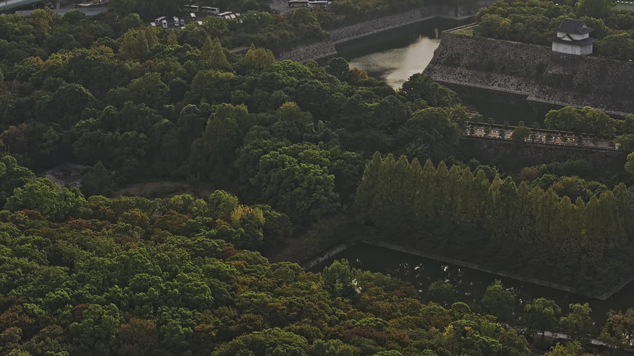 Osaka Japan Aerial v68 zoomed birds eye view, flyover Osakajo capturing blending modern skyscrapers with lush greenery surrounding Osaka Castle at sunset - Shot with Mavic 3 Pro Cine - Oct 9th 2023