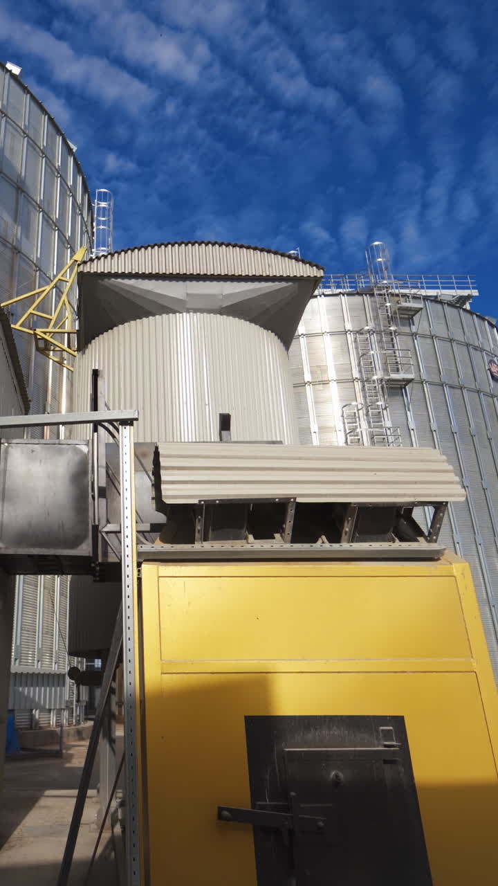 Modern Granary elevator. Silver silos on agro-processing and manufacturing plant for processing drying cleaning and storage of agricultural products, flour, cereals and grain. Vertical video