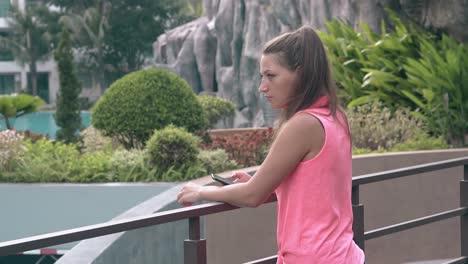 young-girl-with-long-ponytail-stands-by-balcony-metal-fence