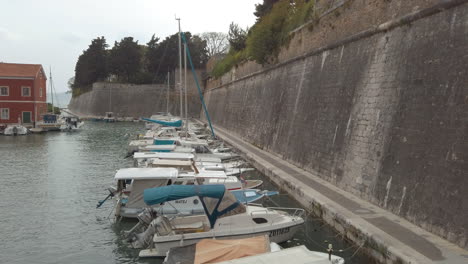 slow tilt revealing small boats in a harbour and ancient old city walls of zadar, croatia