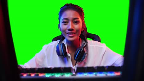 asian gamer woman playing game online and looking at screen on pc computer at home. asian woman controlling console with mouse and keyboard. green screen or chroma key background.