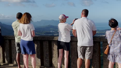 people looking at a view on a windy day at pali lookout, hawaii