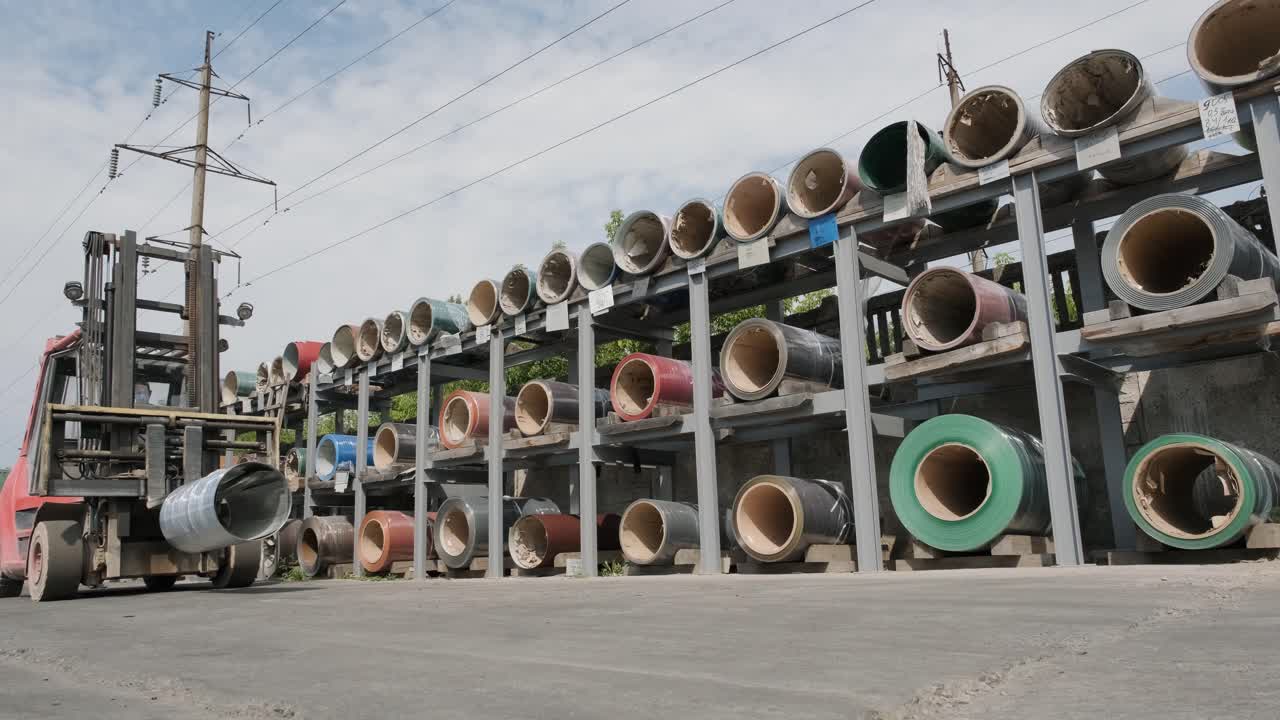 Forklift driver loads Rolls of steel sheet. Industrial warehouse with rolls of steel sheet