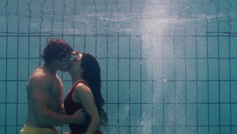 underwater couple kissing in swimming pool young people in love enjoying romantic kiss passionate lovers submerged in water floating with bubbles in playful intimacy