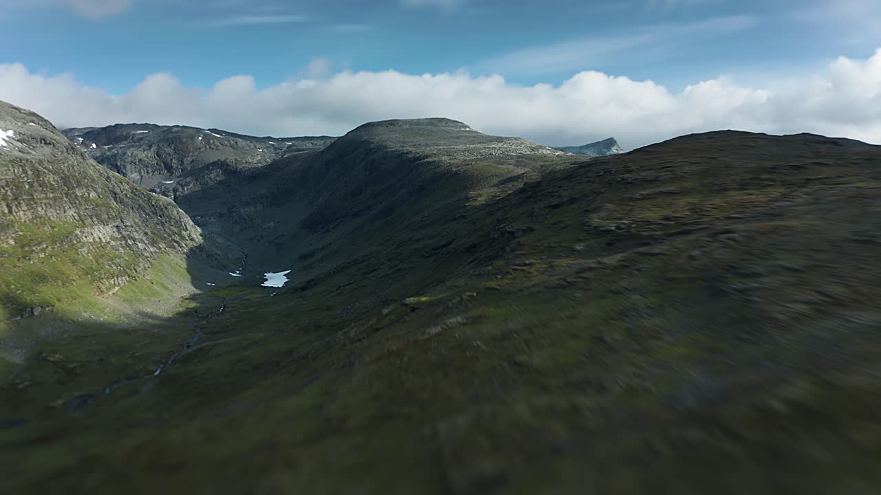 un vuelo rápido hacia adelante sobre el desolado paisaje del norte de la meseta glacial de la montaña aurlandsfjellet con densas nubes tormentosas que se ciernen por encima