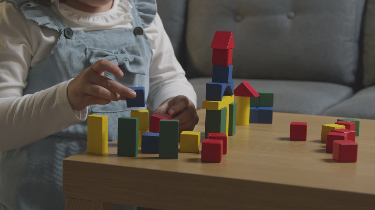 niña en casa jugando con coloridos bloques de construcción de madera 1