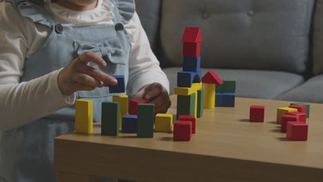 Young-Girl-At-Home-Playing-With-Colourful-Wooden-Building-Blocks-1