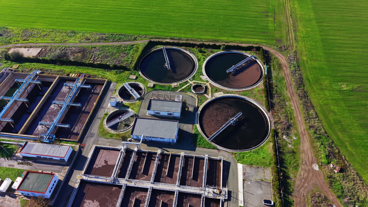 High angle overhead shot of several round settling tanks and rectangular aeration basins at a wastewater processing station. Top down view of circular clarifiers at water treatment facility