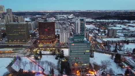 2-3-Luftflieger-über-Abend-Winter-Festliche-Stadt-Flussufer-Historische-Heimatstadt-Park-Skyline-Wald-Natur-Schlittenglocken-Weihnachtsbeleuchtung-An-Gebäuden-Bäume-Gehwege-U-Bahn-System-Unterirdische-Stadtpfade