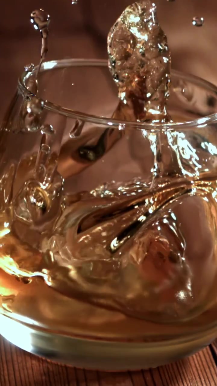 Cubetto di ghiaccio al rallentatore che si tuffa in un bicchiere di whisky
