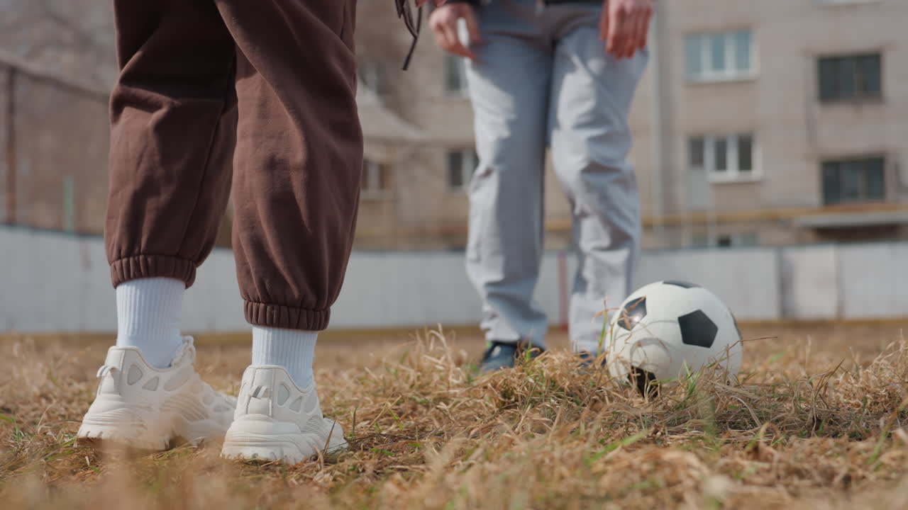 intensa competición con movimientos rápidos en un paisaje urbano, dinámica batalla de fútbol que se desarrolla en una concurrida calle de la ciudad, partido enérgico entre dos jugadores en un campo de juego accidentado