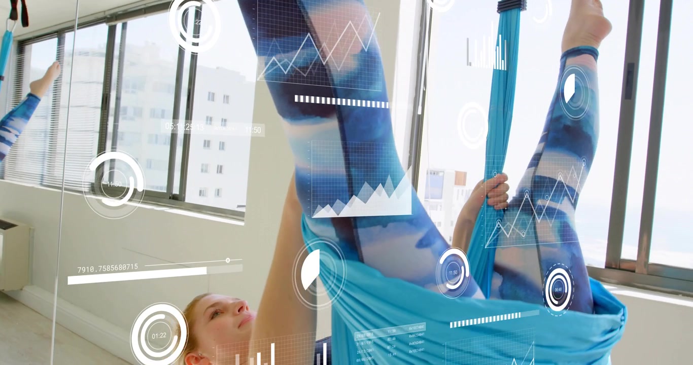 Yoga practitioner entering blue silk hammock and drawing knees inward, inverting body for fitness