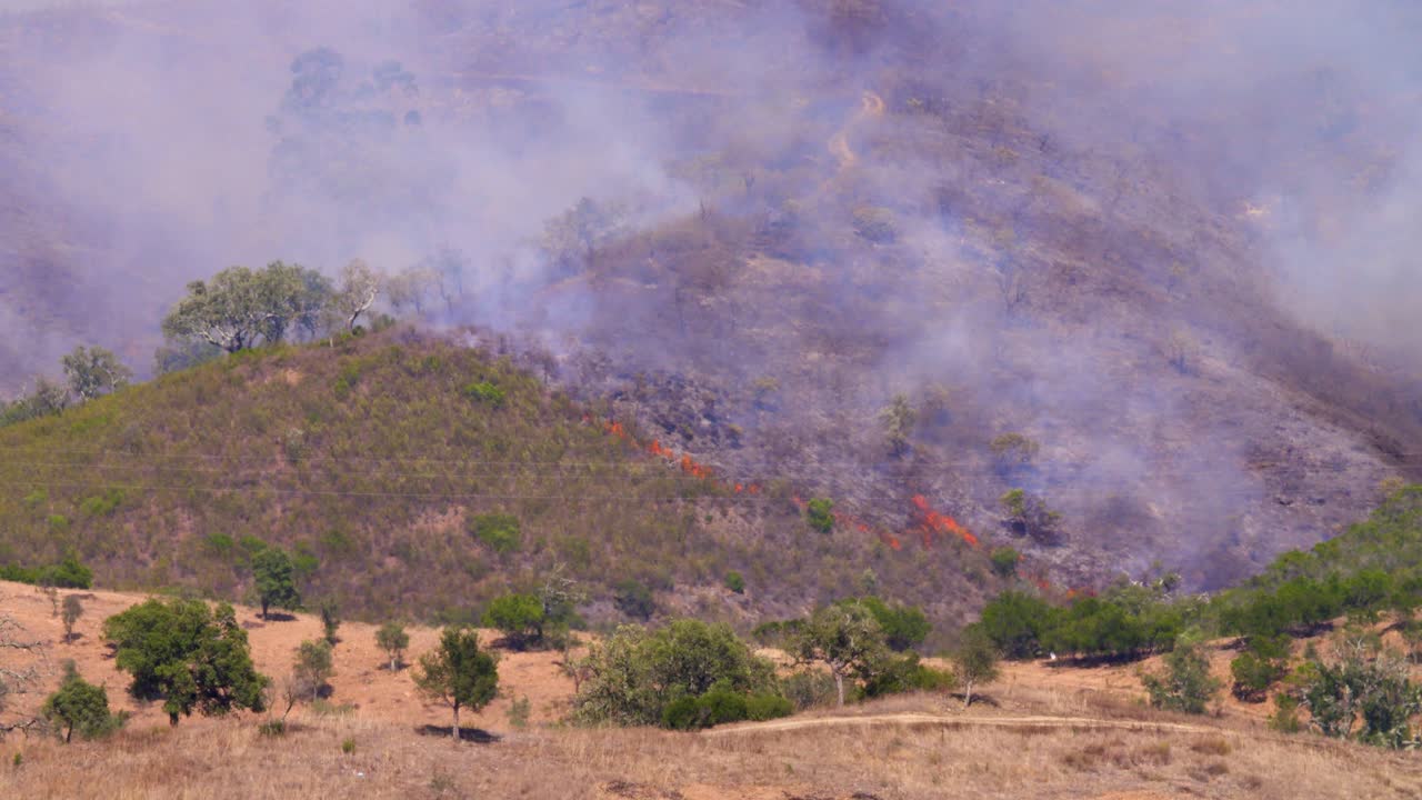 una montaña quemada con la parte inferior todavía en llamas y el aire todavía vibrando por el calor