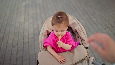 una niña linda sentada en un cochecito y comiendo un bocadillo
