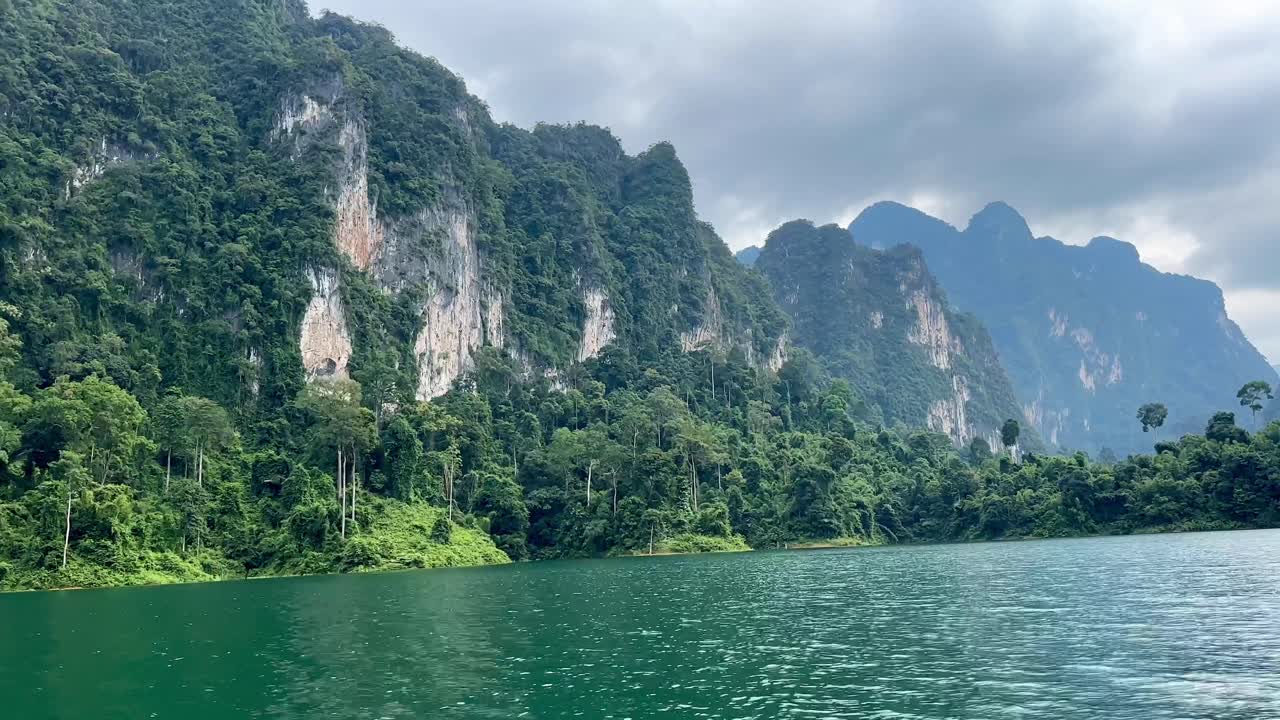 In Thailand's Khao Sok National Park, the viewer captures dense vegetation-covered mountains from a moving boat&mdash;a cinematic journey through the lush landscapes