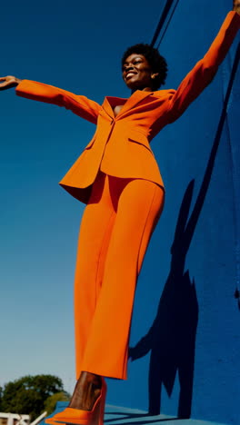 vibrant orange suit fashion against a blue wall