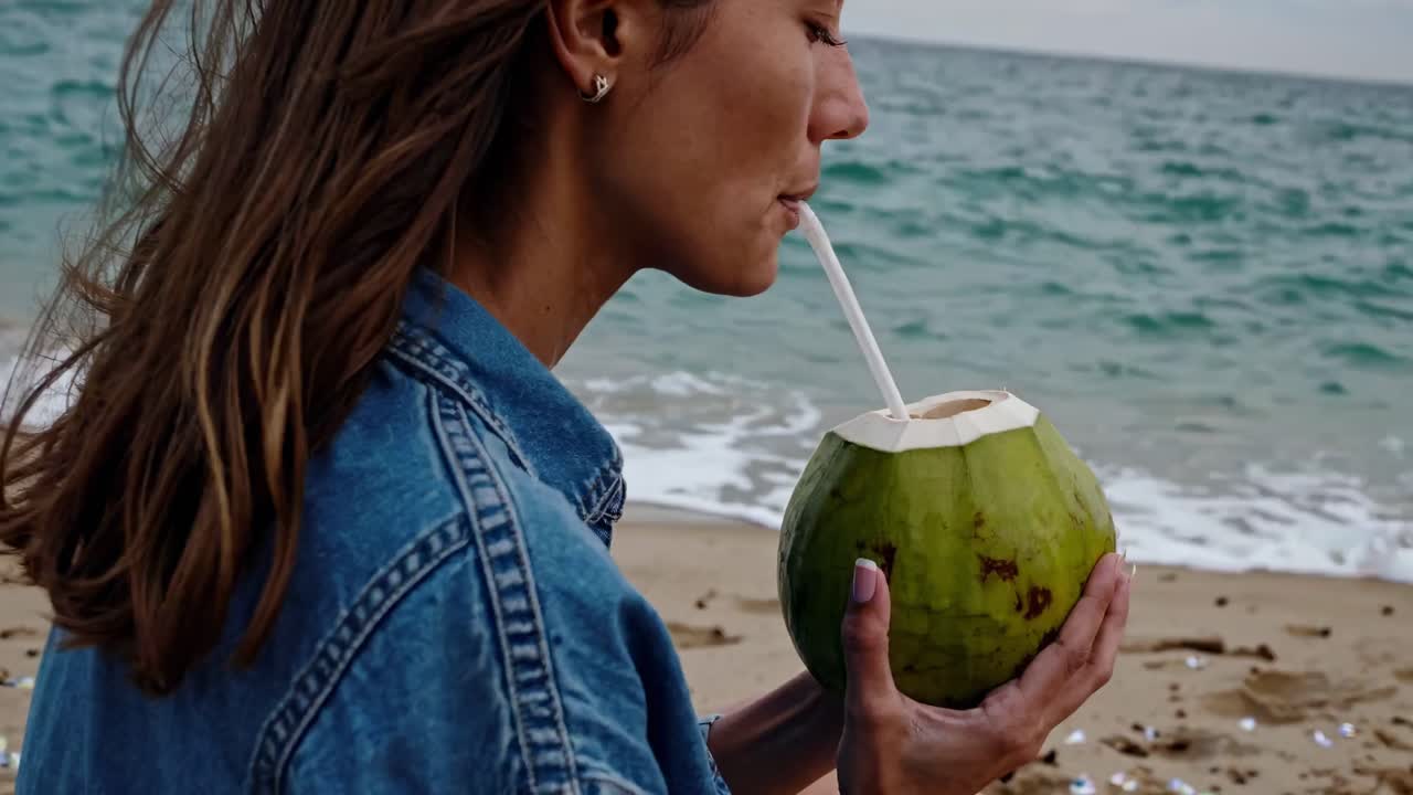 mujer bebiendo agua de coco en la playa