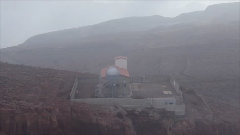 toma aérea de la cúpula del observatorio temisas donde la niebla cubre parcialmente la cúpula