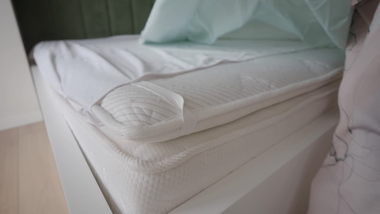 Making a bed with a mattress topper and fresh sheets