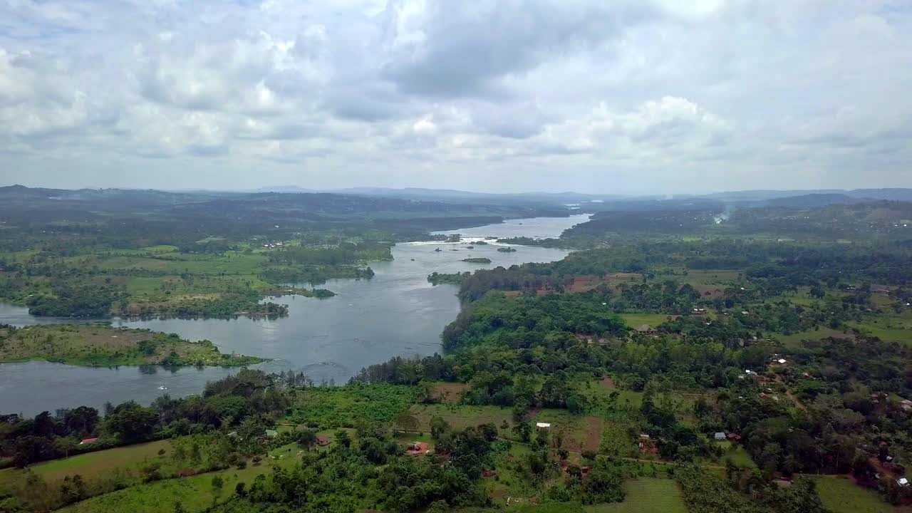 Drone establishing shot of the Nile River winding through Uganda’s lush countryside, showing farmlands and forests under soft clouds at the river’s source, a serene view of the world’s longest river