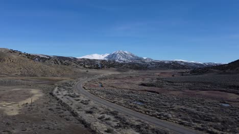 drone shot of a snow-covered mountain towering over the hills and valley below in northern nevada. the mountain is contrasted by the highway and the river, tying together this wild rural landscape.