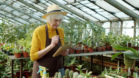 senior gardener taking notes in greenhouse