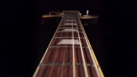 slow tracking shot up the fretboard of a gibson les paul electric guitar with the camera moving towards the guitar body
