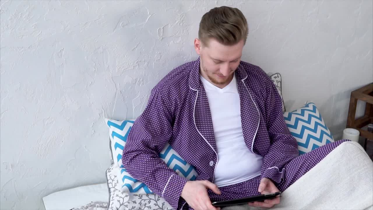 Man in pajamas using tablet in bed