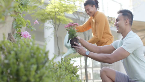 Happy-diverse-gay-male-couple-gardening-in-sunny-garden,-copy-space,-slow-motion,-copy-space