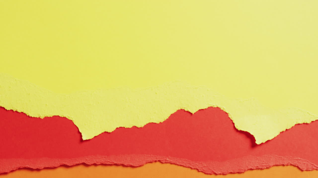 Video of close up of torn pieces of yellow, red and brown paper background