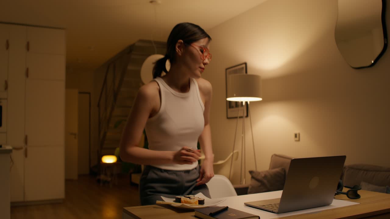 mujer trabajando desde casa, comiendo sushi por la noche